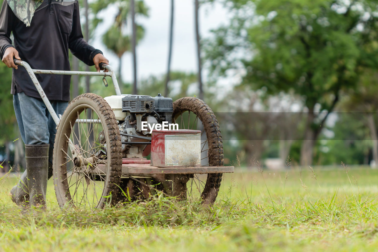 Thai worker mowing grass with machine in the public garden