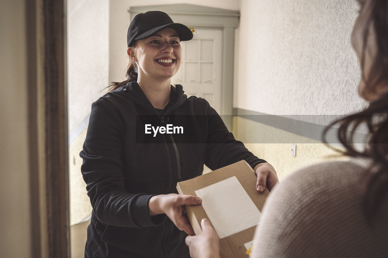 Smiling woman delivering package to customer at doorstep