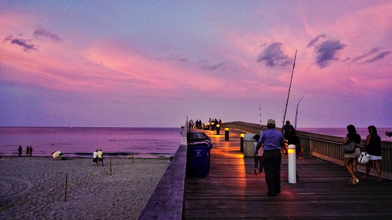 REAR VIEW OF PEOPLE WALKING ON PIER