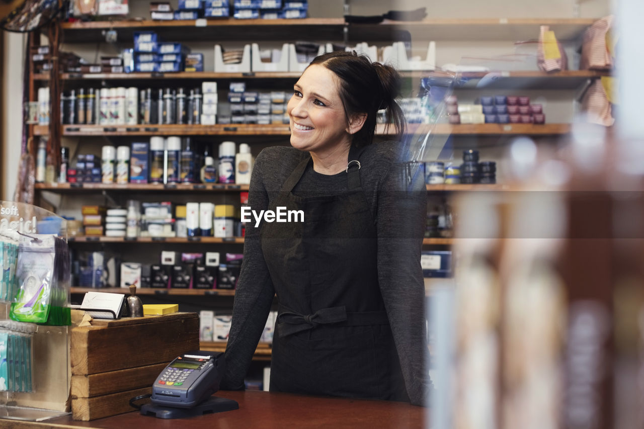 Smiling woman looking away while standing in repair shop