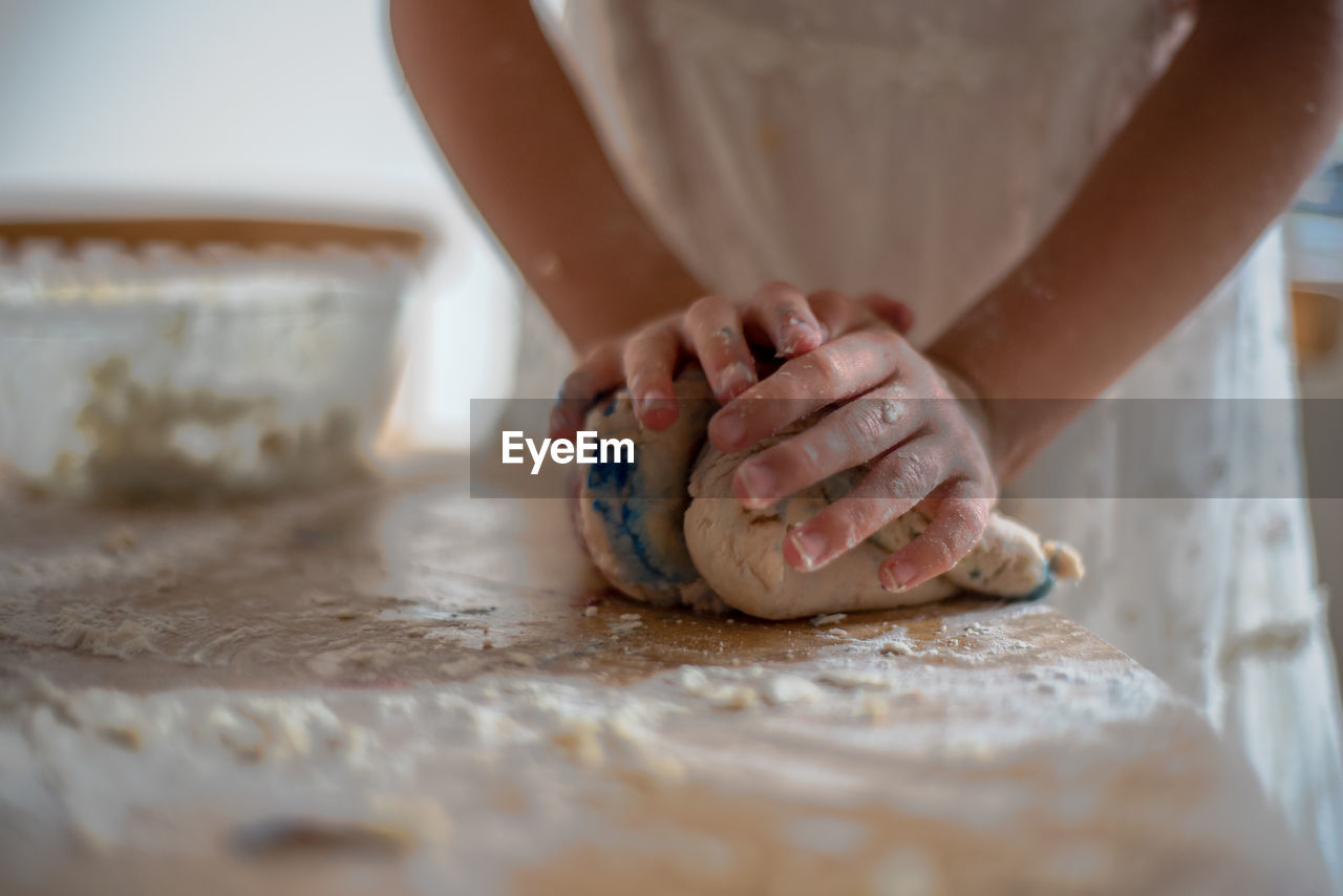 Midsection of woman kneading dough on table