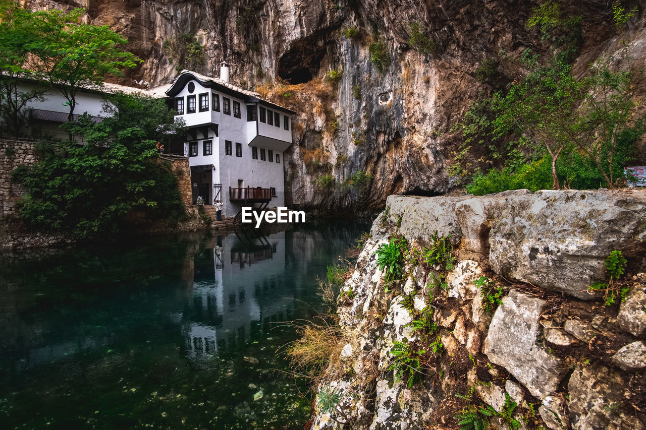 HOUSE BY RIVER AGAINST BUILDINGS