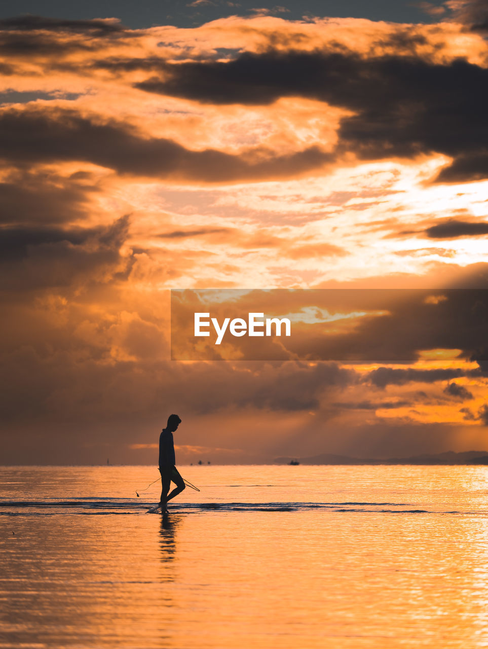 Silhouette man on sea against sky during sunset