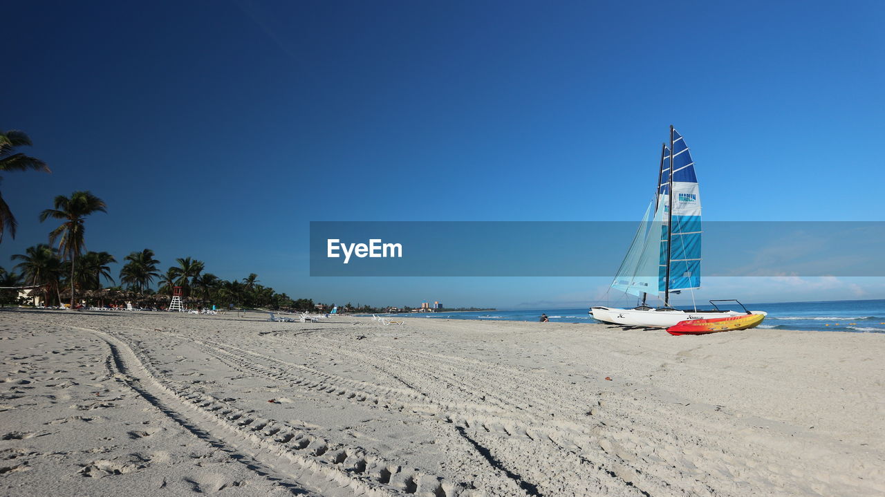 SAILBOAT ON BEACH AGAINST BLUE SKY
