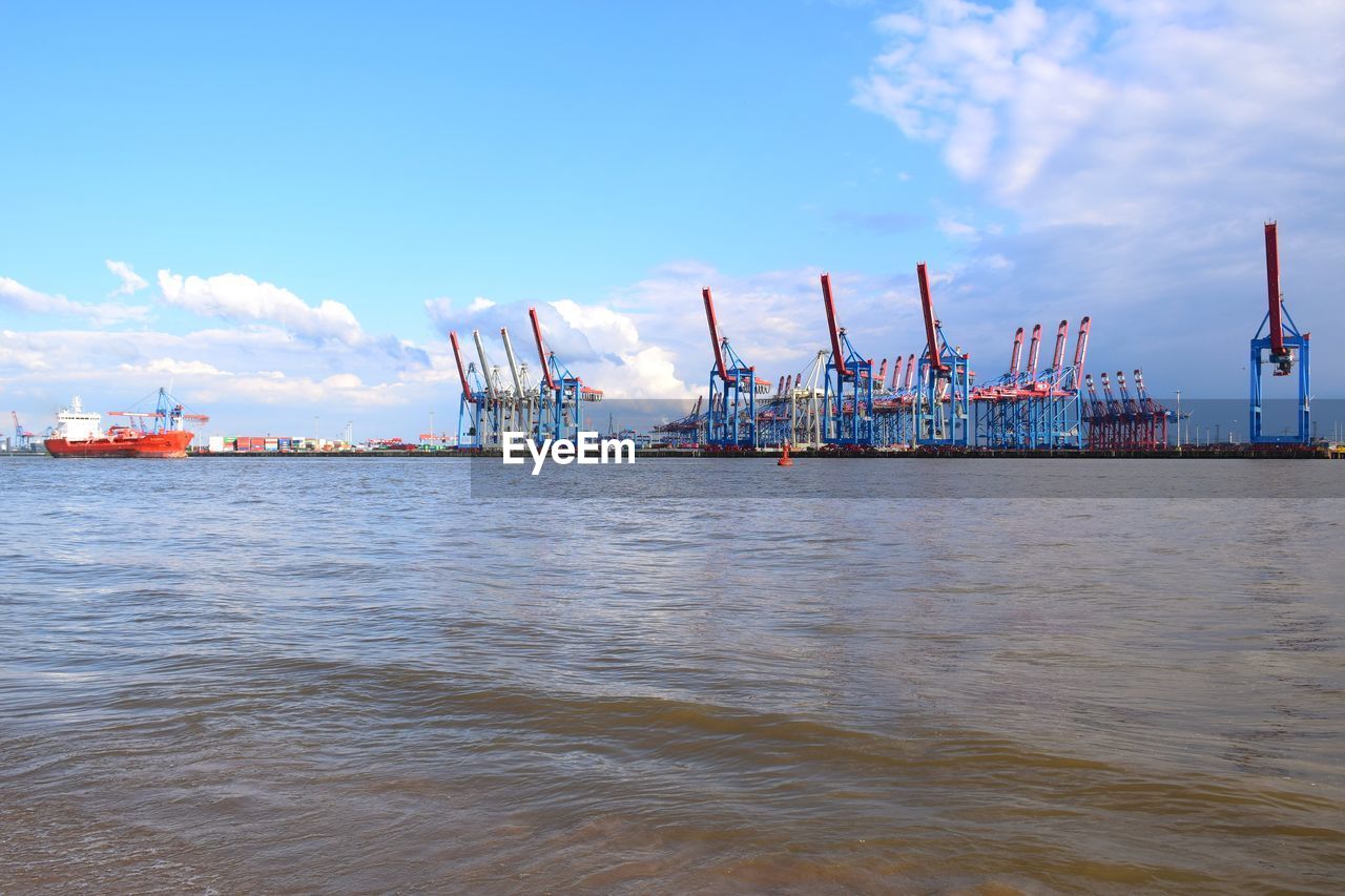 Cranes at commercial dock against sky