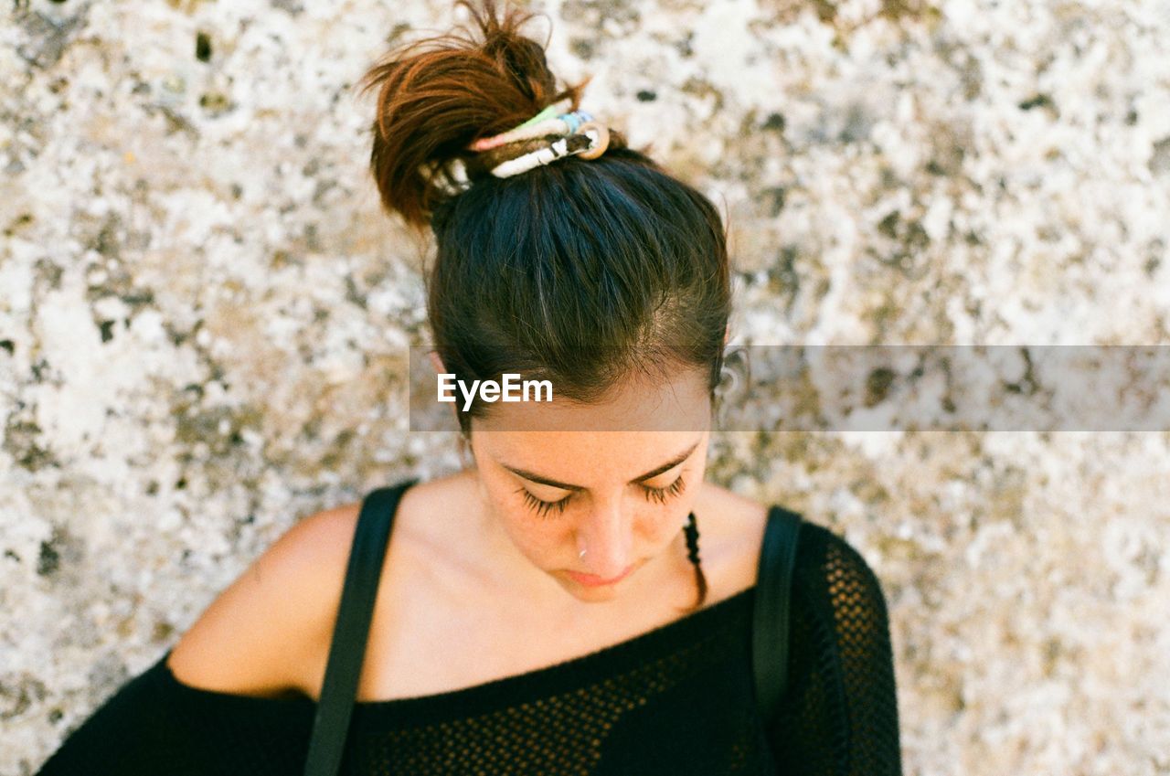 Close-up of young woman standing against wall