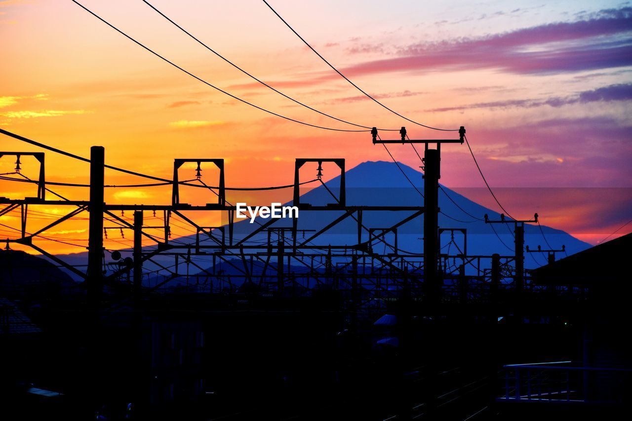 LOW ANGLE VIEW OF POWER LINES AGAINST SUNSET