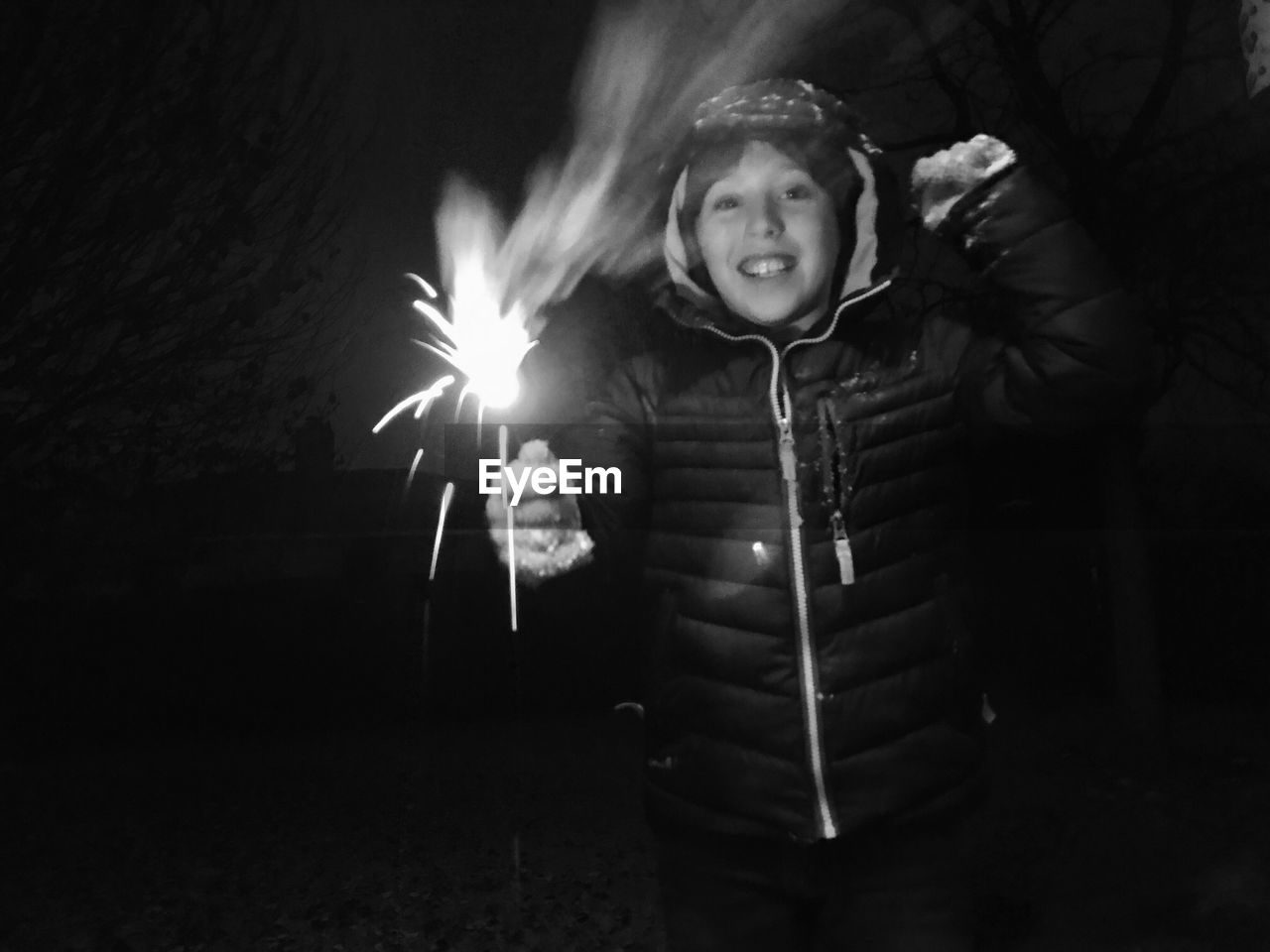 Cheerful boy holding sparkler outdoors