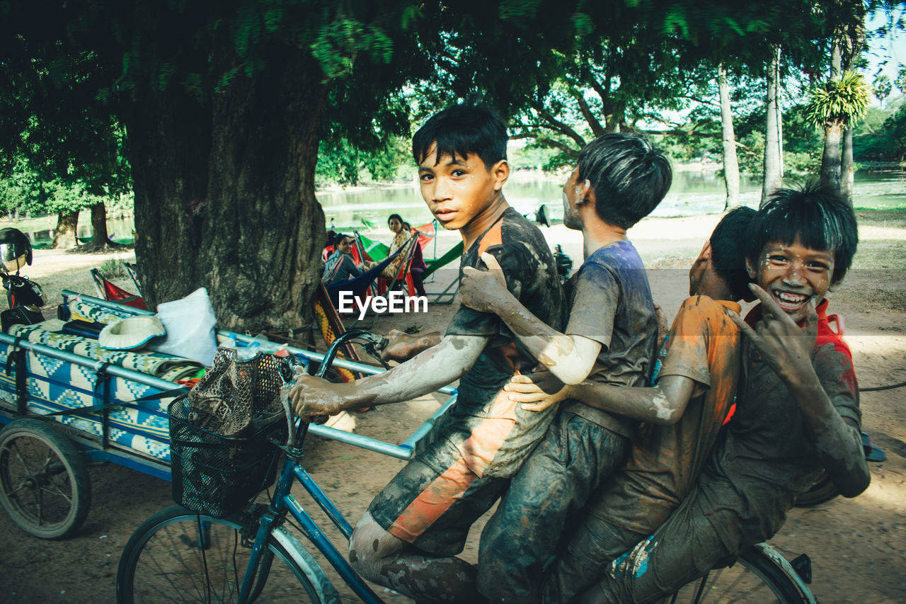 PEOPLE SITTING IN CART BY TREES