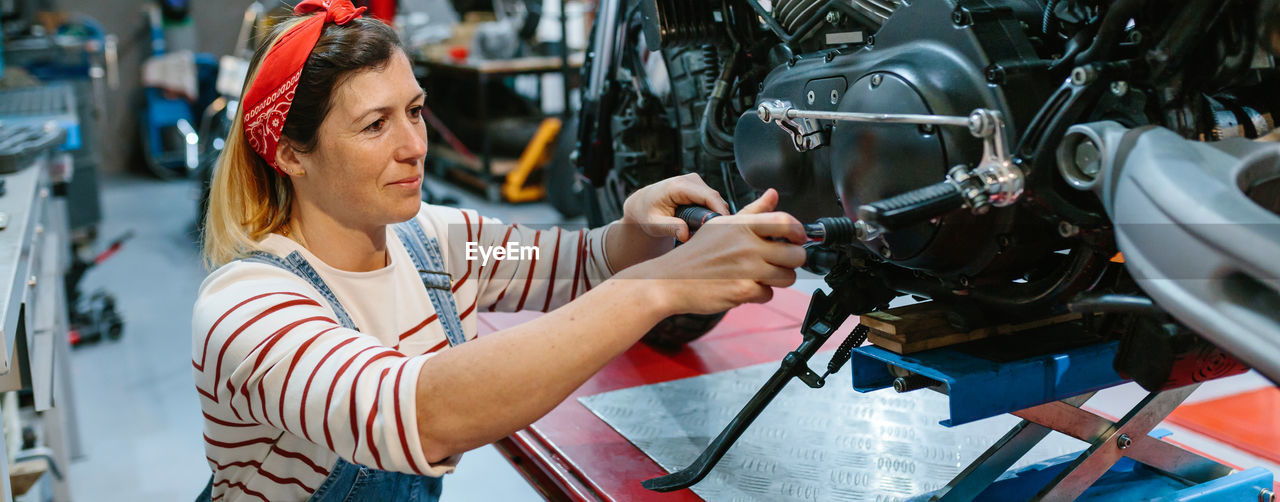 Mechanic woman reviewing motorcycle over platform