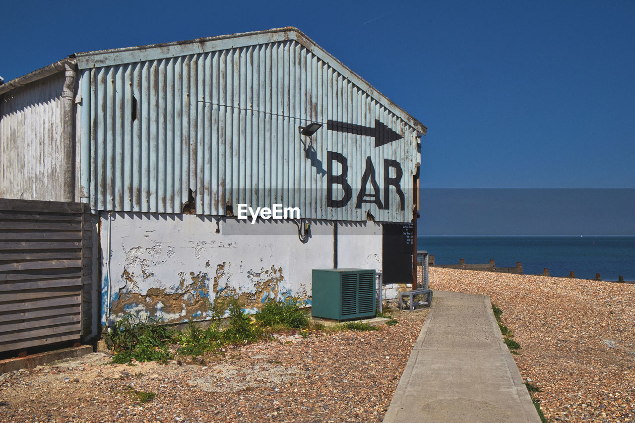 SIGN ON BEACH AGAINST CLEAR SKY