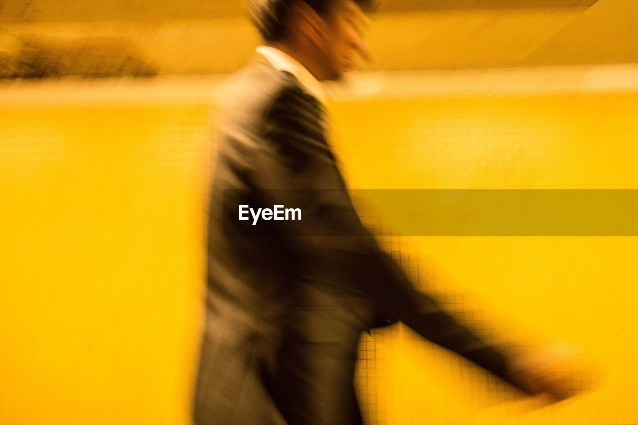 BLURRED IMAGE OF PERSON WALKING ON YELLOW FLOOR