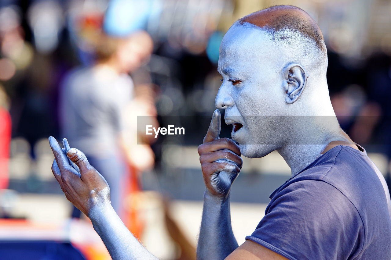 CLOSE-UP PORTRAIT OF MAN HOLDING MOBILE PHONE OUTDOORS