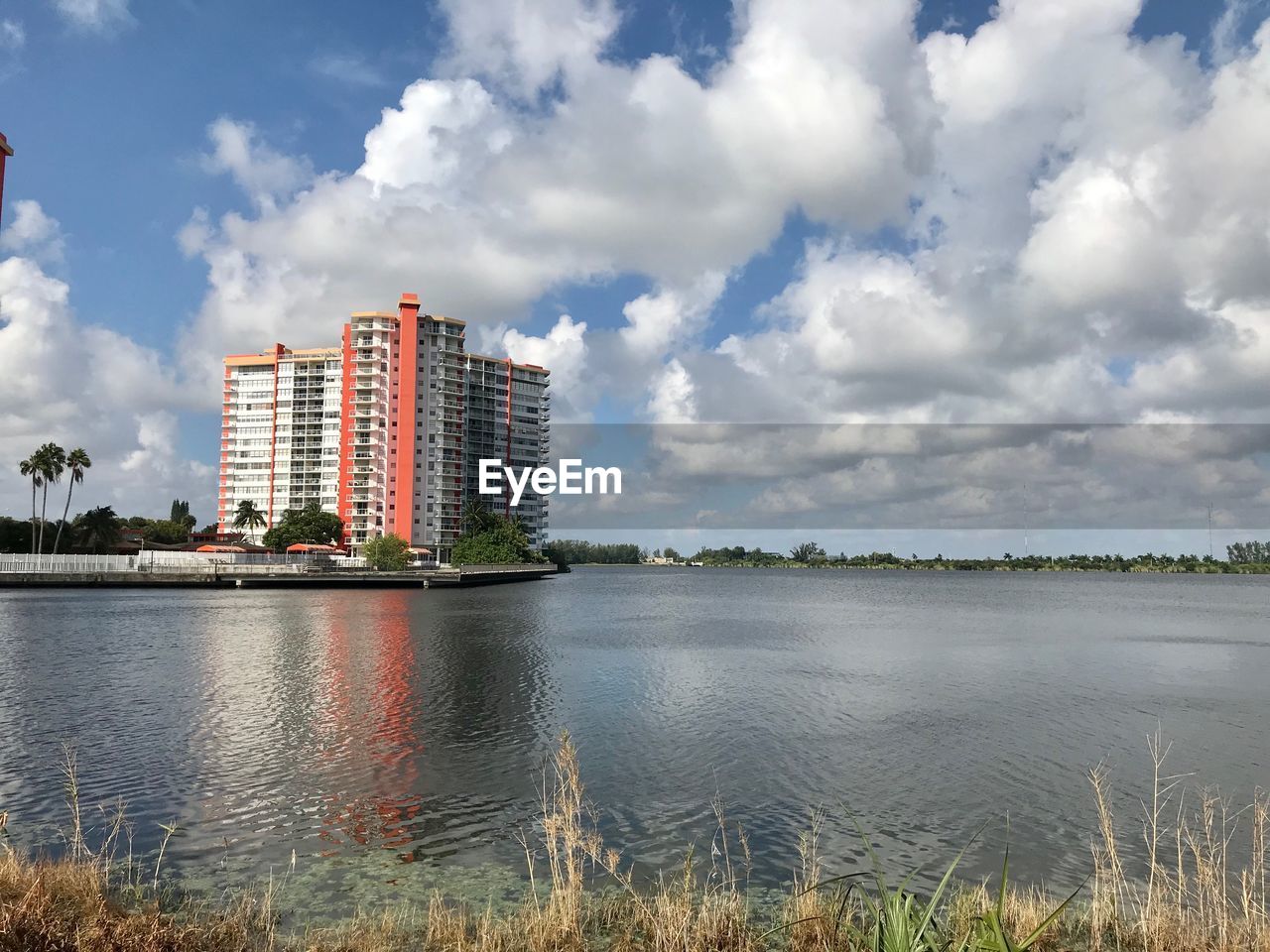 Buildings by lake against sky in city