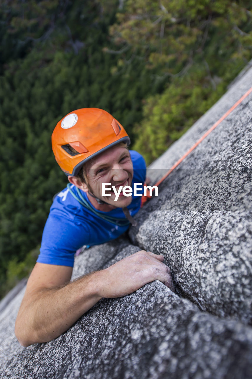 Climber looking up and laughing while rock climbing with helmet chief