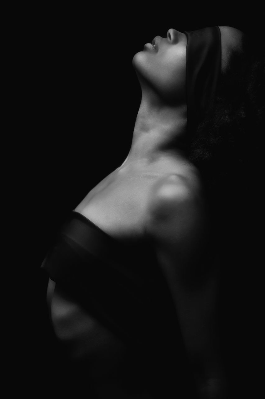 Side view of sensuous woman with ribbons against black background