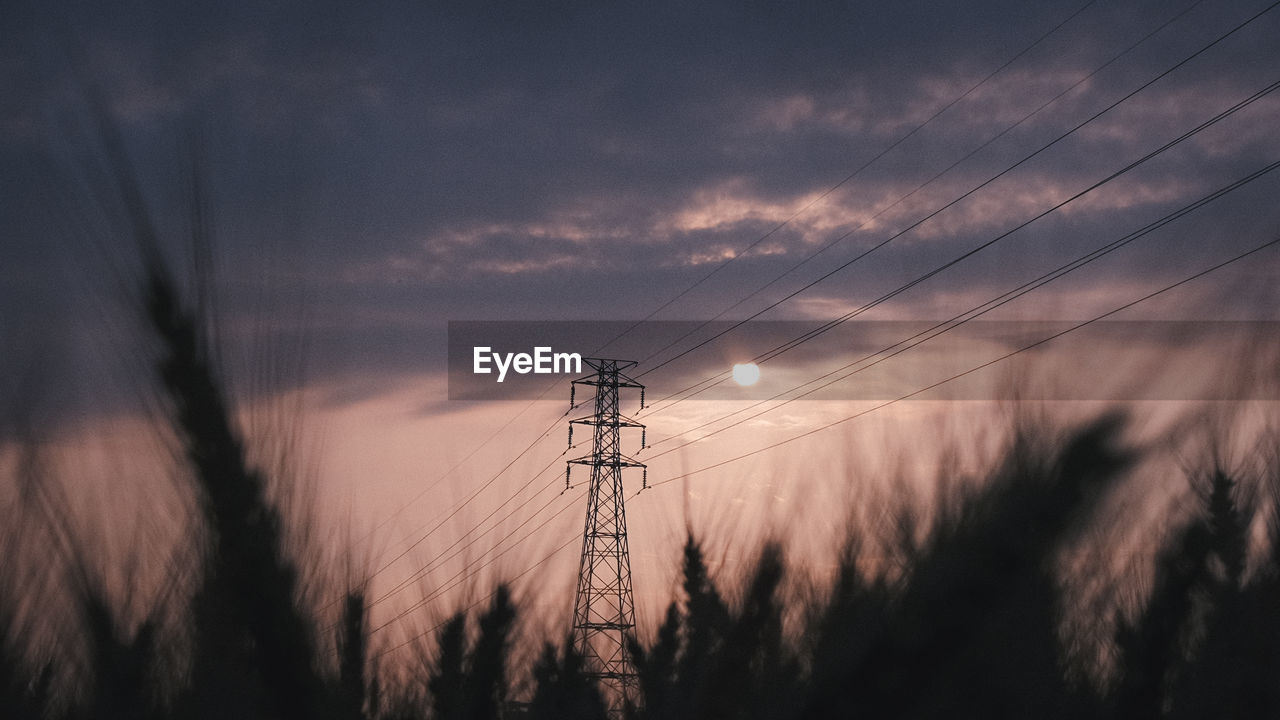 LOW ANGLE VIEW OF ELECTRICITY PYLON AGAINST SKY AT SUNSET