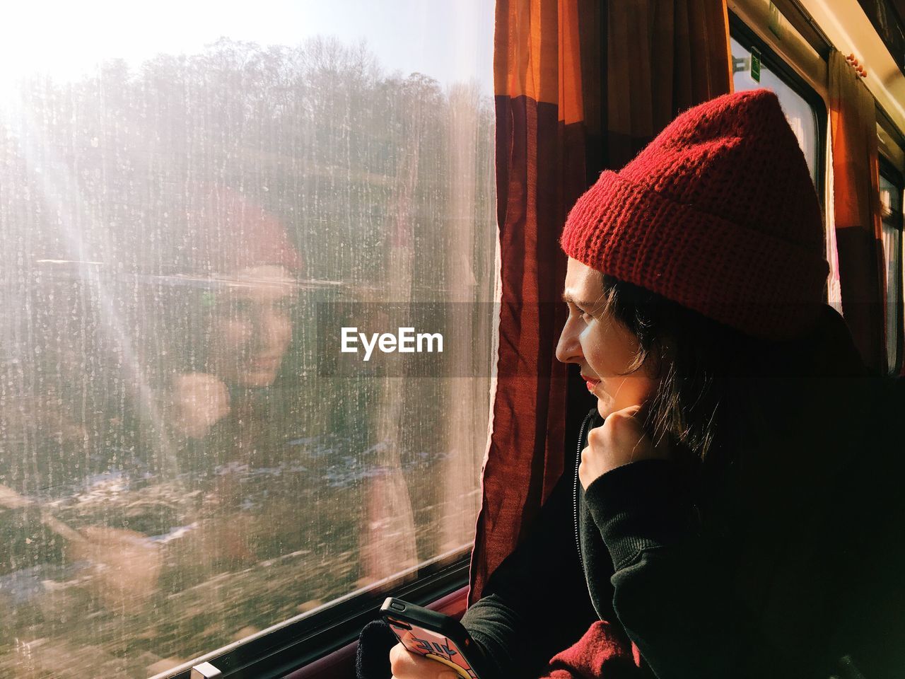 Young woman wearing knit hat sitting in train