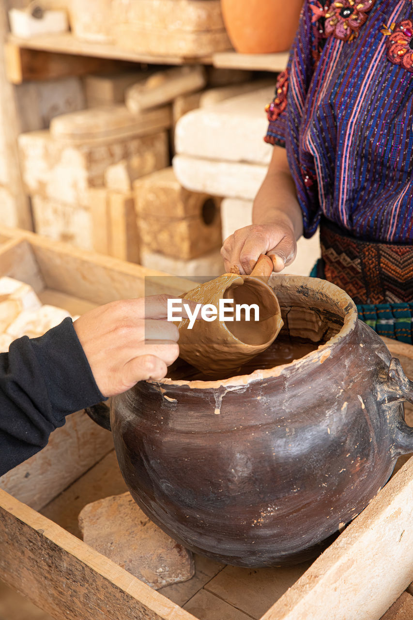 Close up of a female hand holding a hand made ceramic mug while a male hand touches it