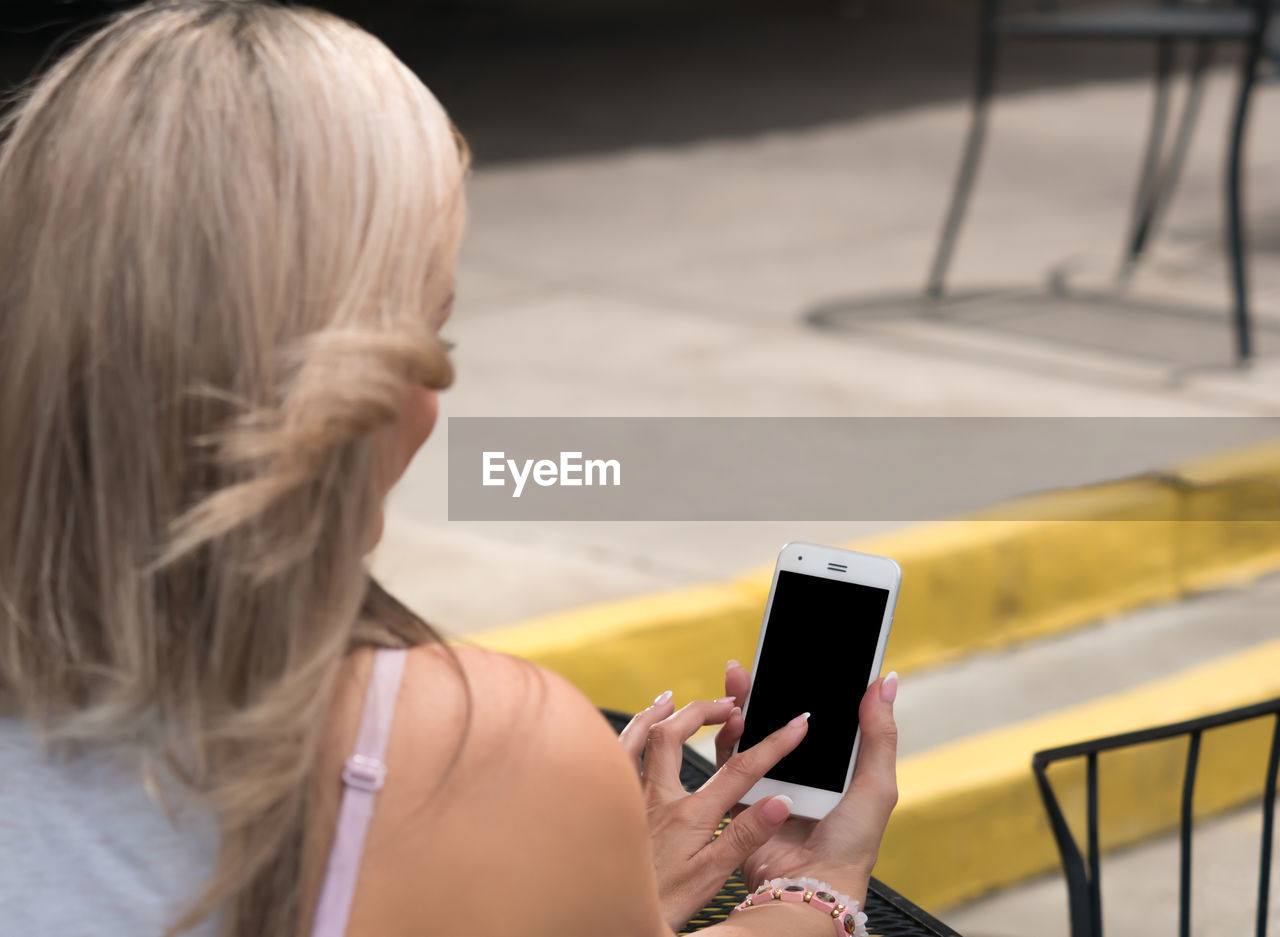 Woman using mobile phone while sitting outdoors