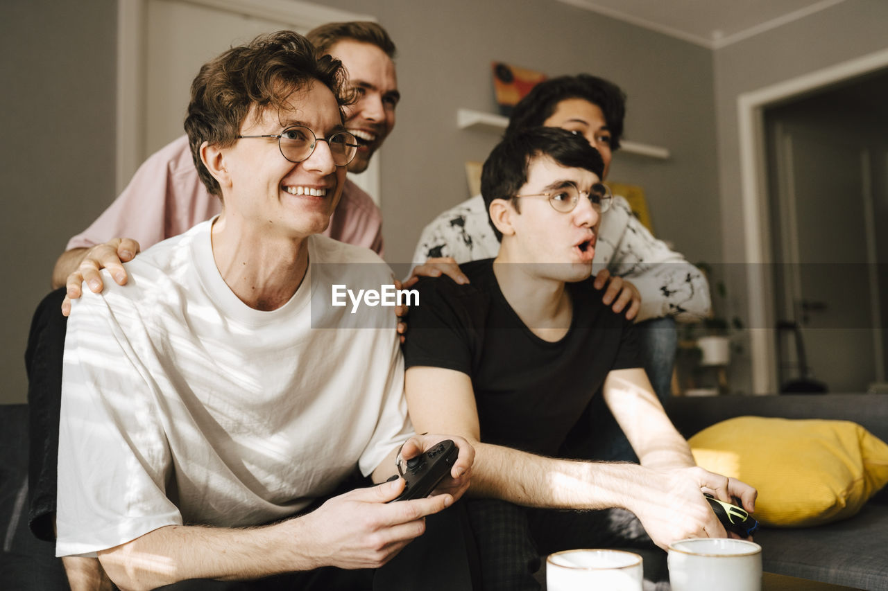 Happy male friends playing video game at home