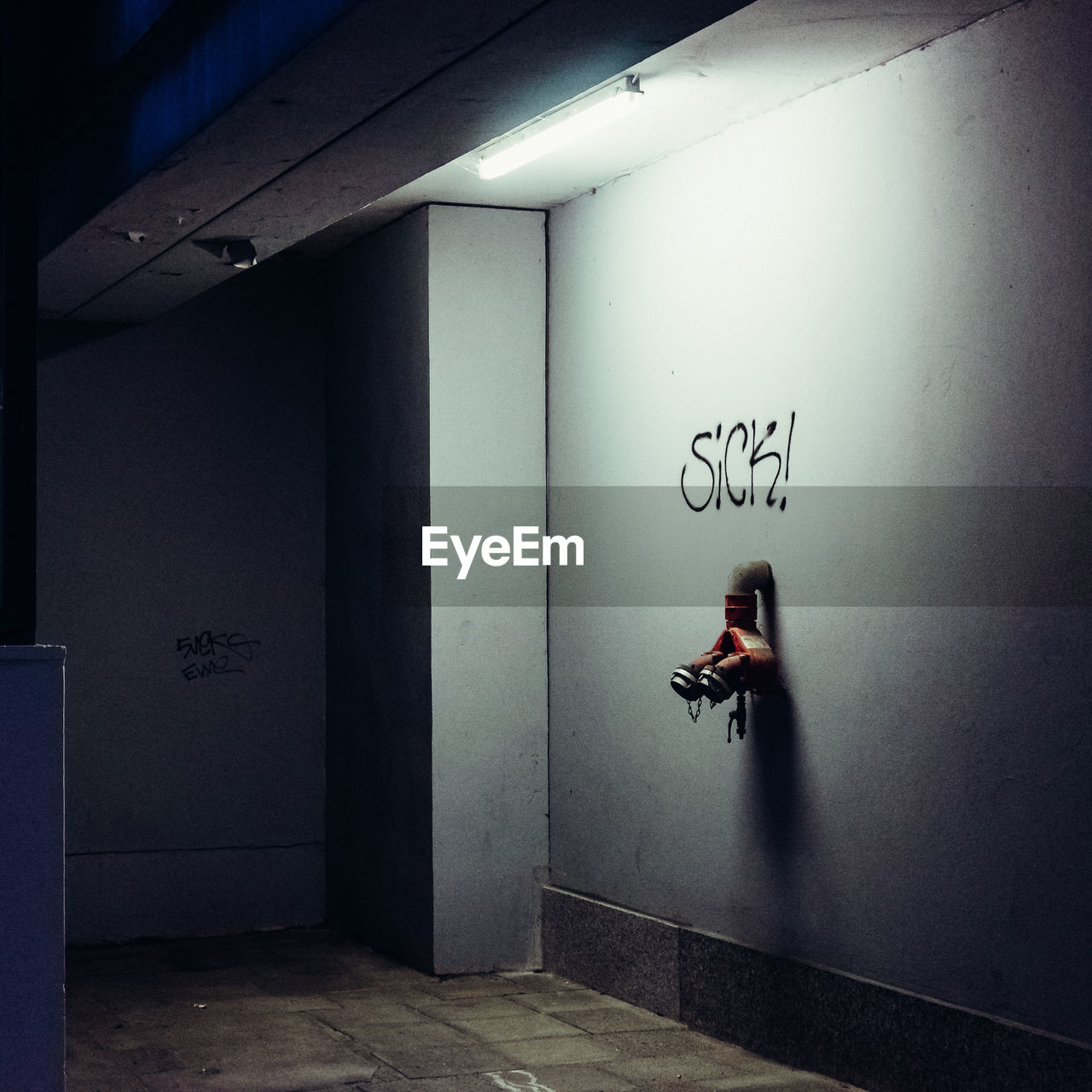 MAN WITH TEXT ON WALL IN ILLUMINATED ROOM