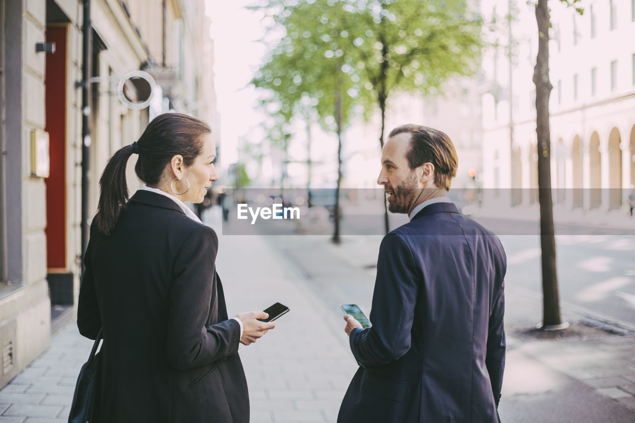 Rear view of business people standing on sidewalk