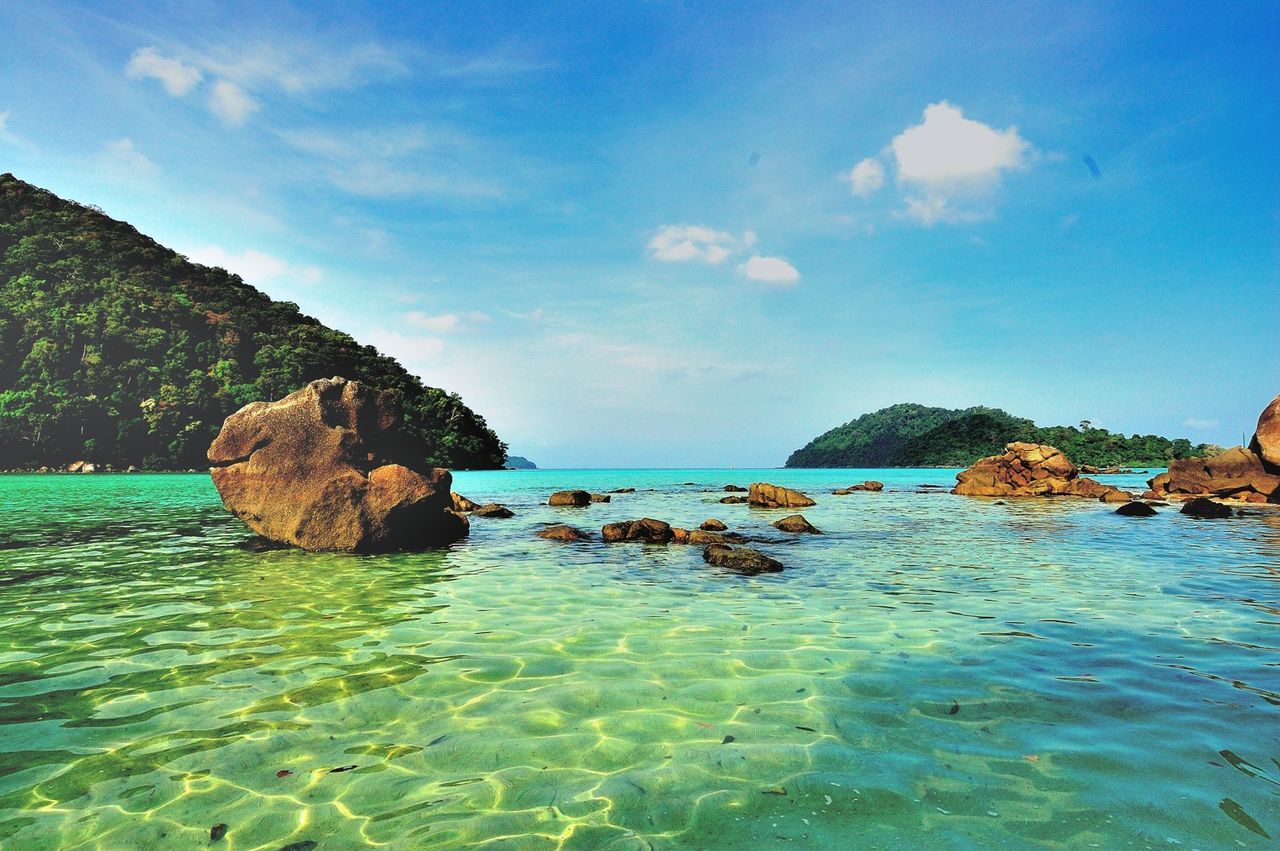 Rocks in sea against blue sky