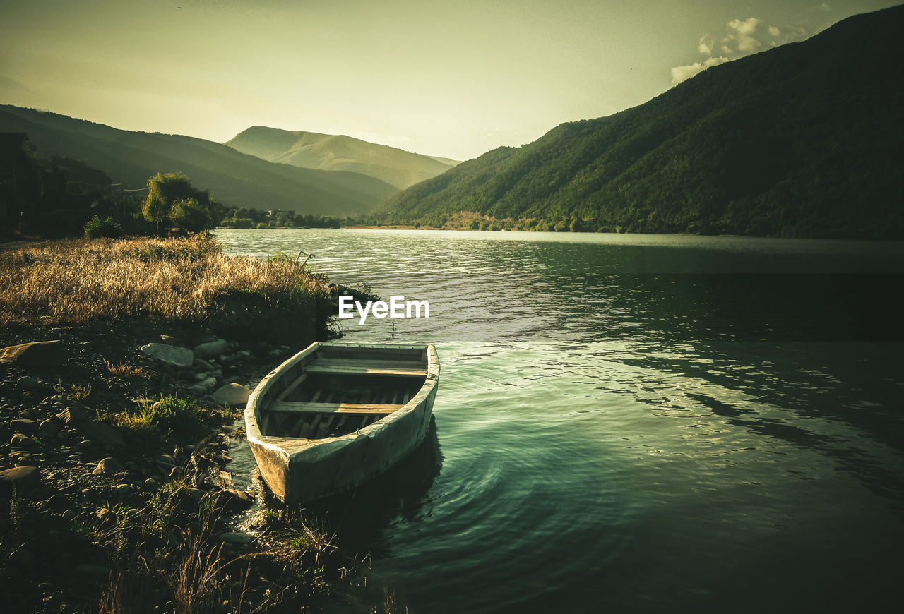 Boat moored on lake against sky