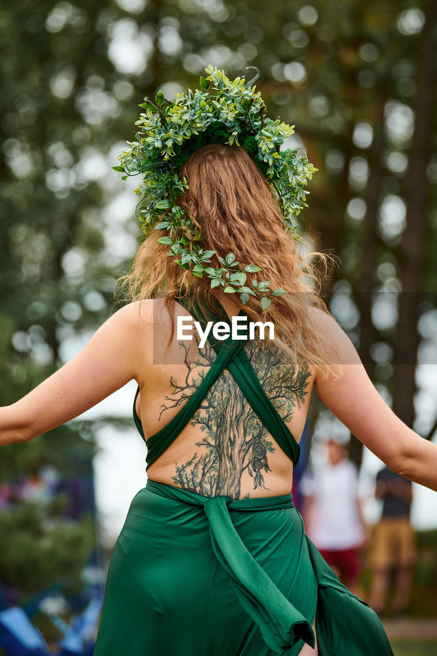 green, adult, women, one person, hairstyle, clothing, long hair, young adult, plant, nature, dancing, arts culture and entertainment, fashion, female, lifestyles, tree, focus on foreground, outdoors, rear view, summer, leisure activity, spring, blond hair, portrait, person, flower, day, emotion, dress, event, sports, costume, fun, carefree, individuality