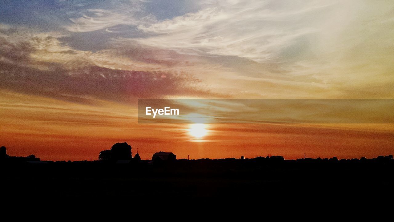 Silhouette landscape against orange sky during sunrise