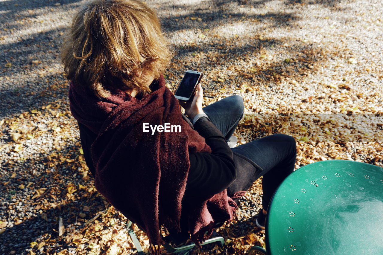 High angle view of young man using mobile phone while sitting outdoors