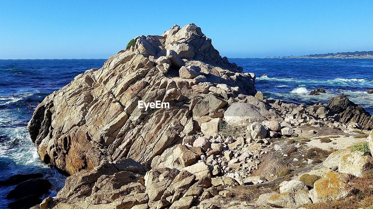 ROCK FORMATION BY SEA AGAINST CLEAR SKY