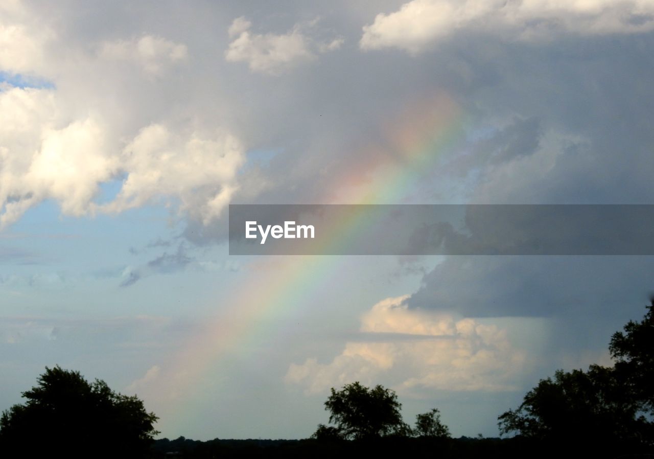 LOW ANGLE VIEW OF RAINBOW AGAINST CLOUDY SKY