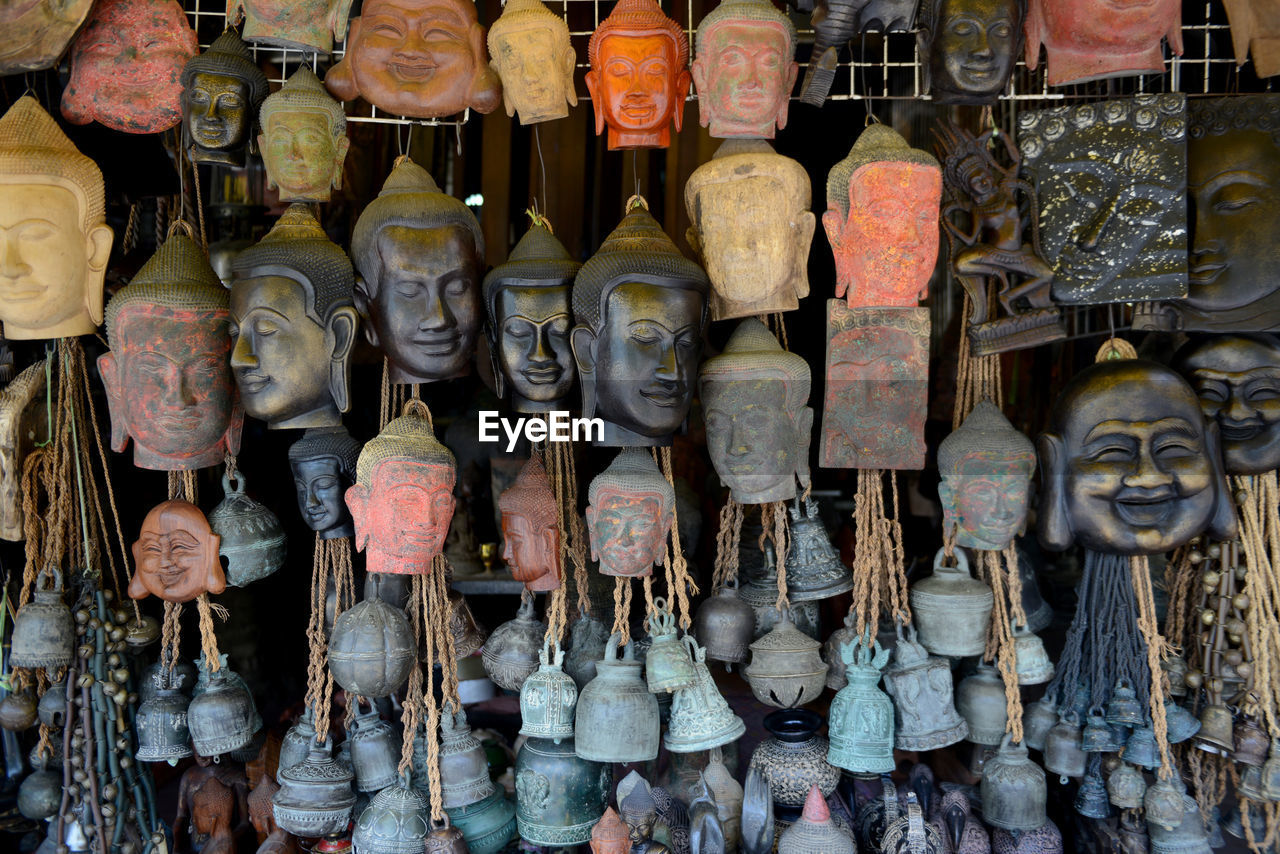 Buddha bust and bells hanging at market for sale