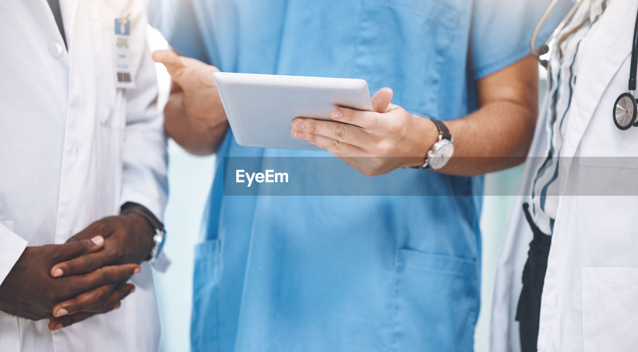 midsection of doctor holding stethoscope while standing in hospital