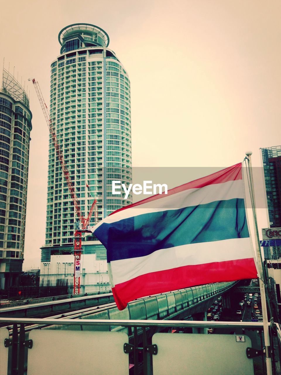 Thai flag by skyscrapers under construction against clear sky