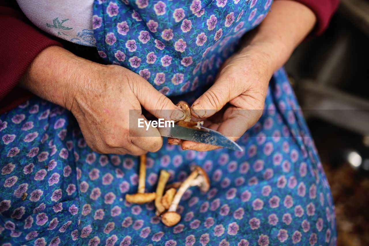 Midsection of woman cutting mushrooms at home