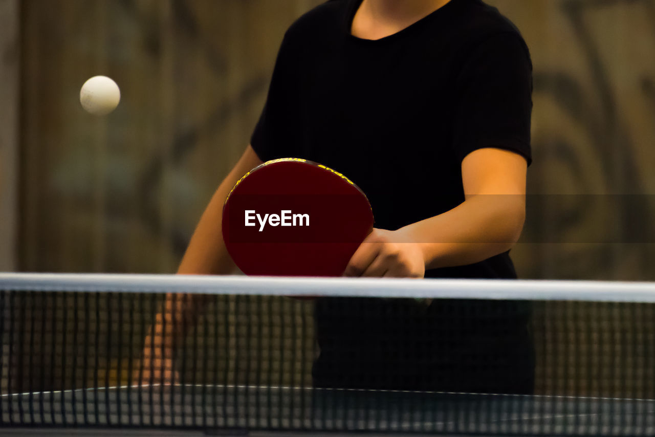 Midsection of man playing table tennis