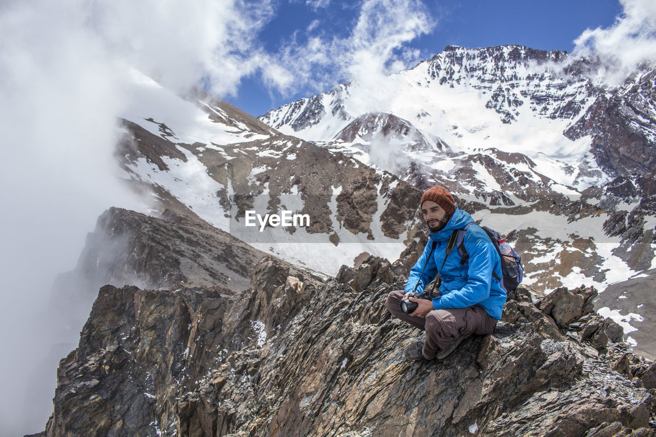 WOMAN ON SNOWCAPPED MOUNTAINS AGAINST SKY