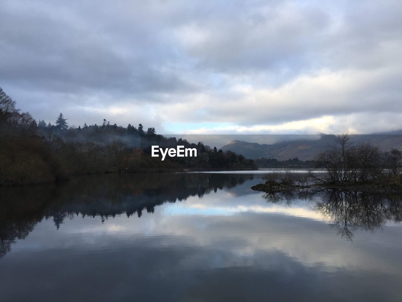 REFLECTION OF TREES IN LAKE AGAINST SKY