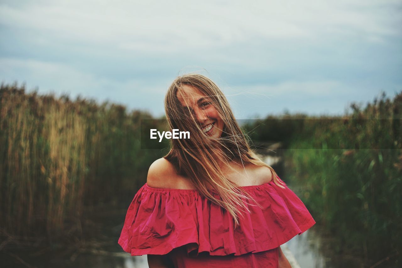 Beautiful young woman standing against sky