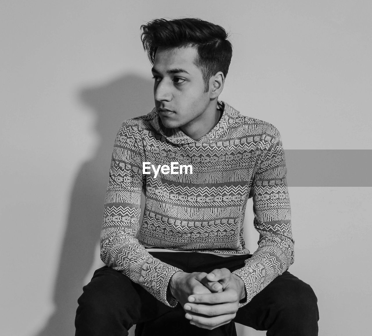 Thoughtful young man sitting against wall