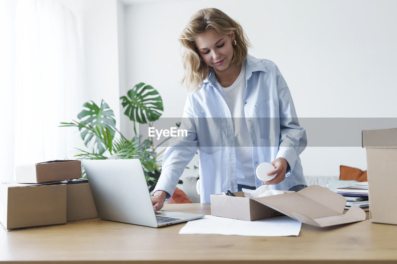 Young businesswoman doing merchandise inventory in laptop at home office