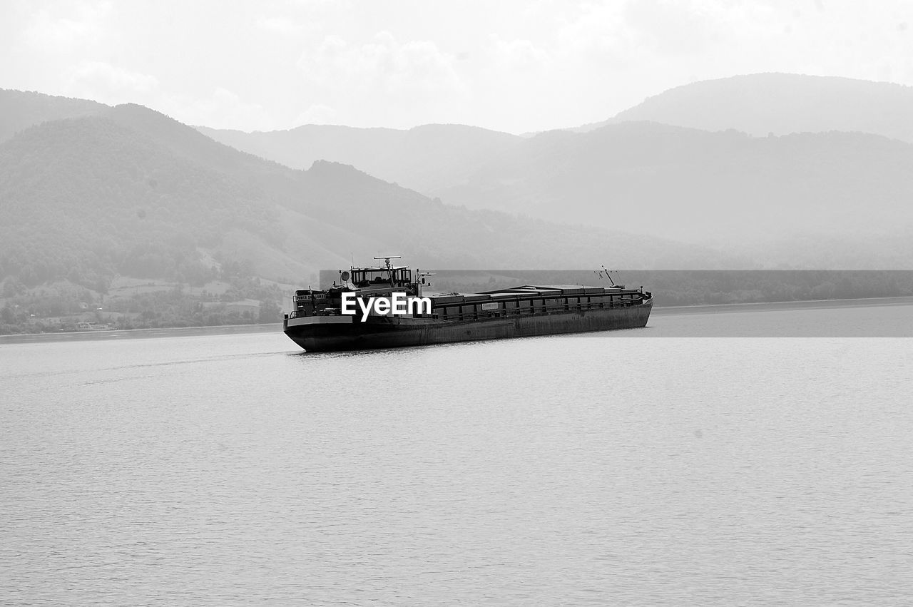 Barge sailing on danube river against mountains in foggy weather