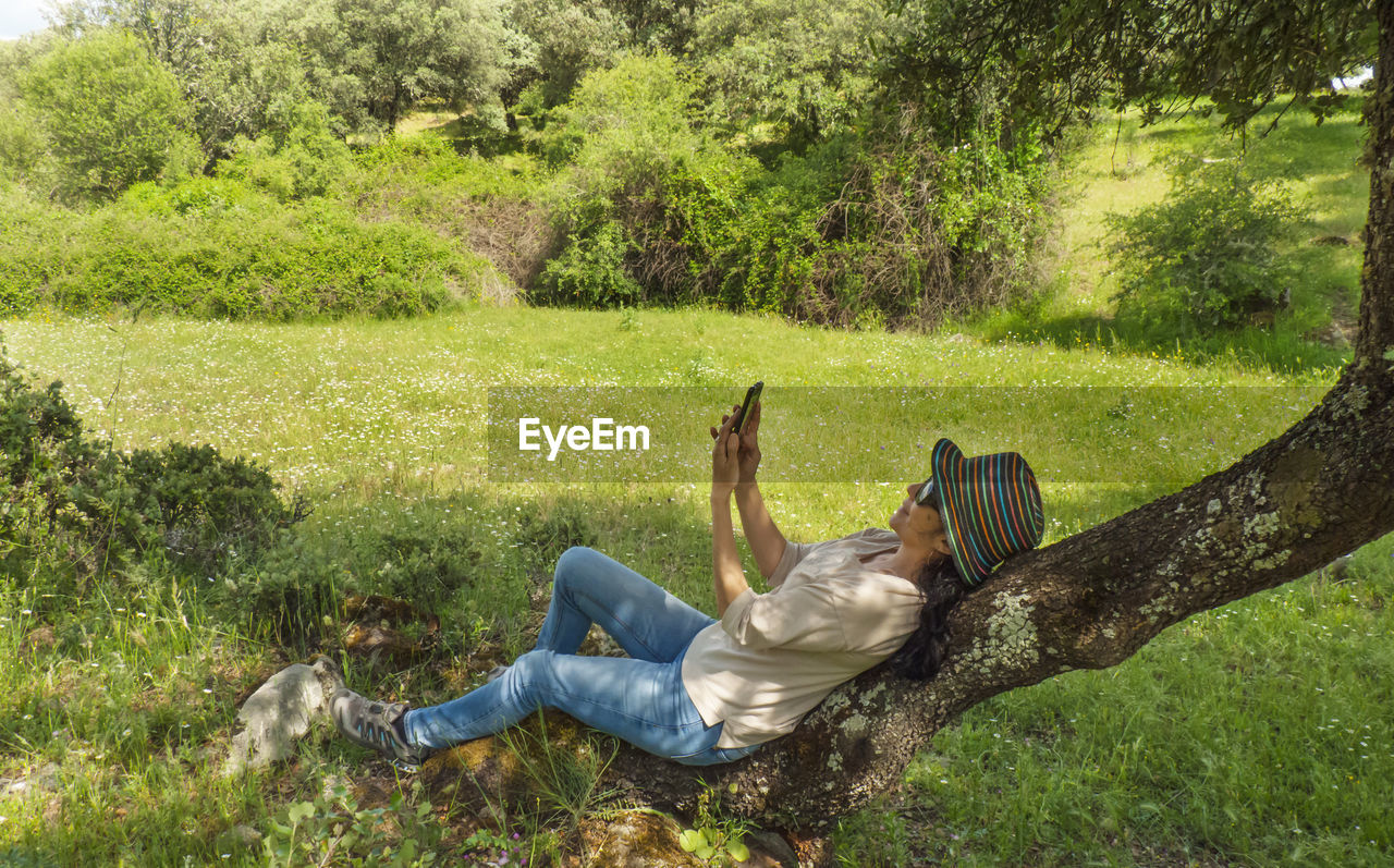 Woman taking selfie from phone on tree at land