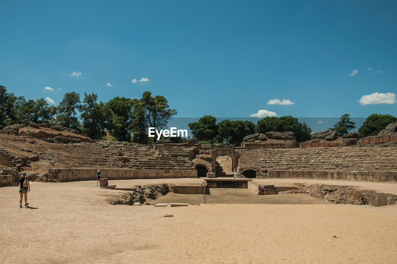 People walking around the arena of roman amphitheater in a sunny day at merida, spain