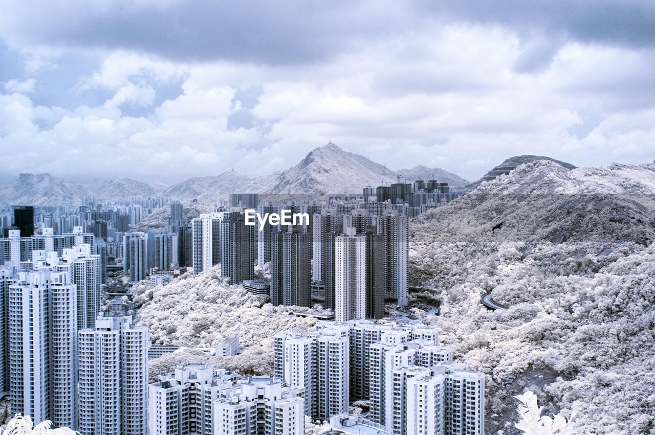 High angle view of cityscape and mountains against cloudy sky