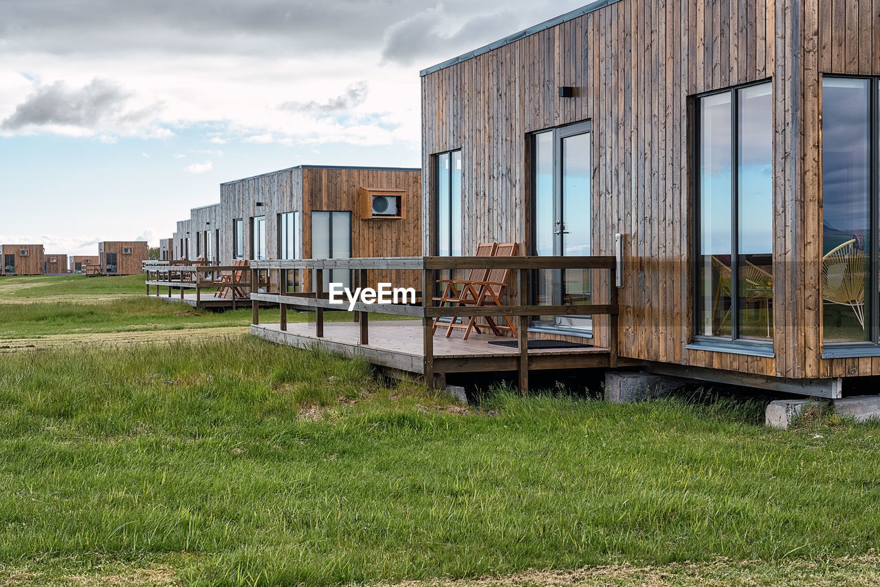 Stylish residential houses cabin with glass panoramic windows and terraces located on green grassy field in countryside of iceland in hvolsvollur