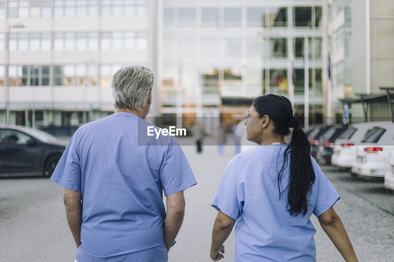 Rear view of male and female doctors walking towards hospital building